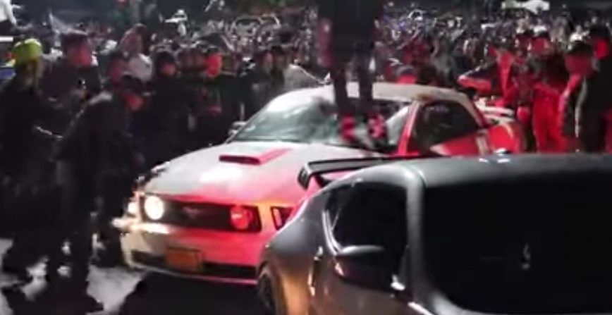 Guy on top of mustang with crowd 