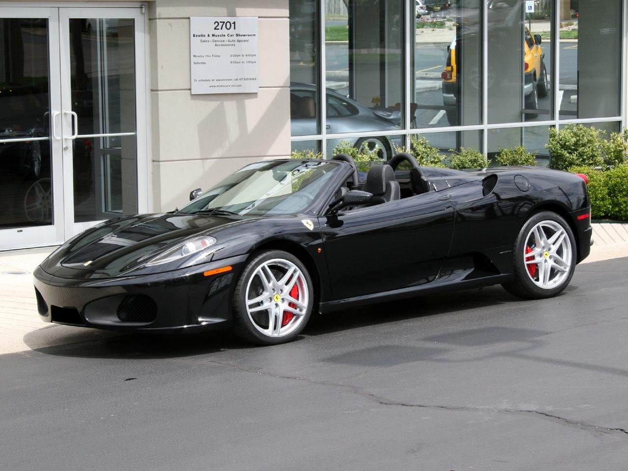 Simon Cowell's black Ferrari F430 Spider convertible parked next to a building