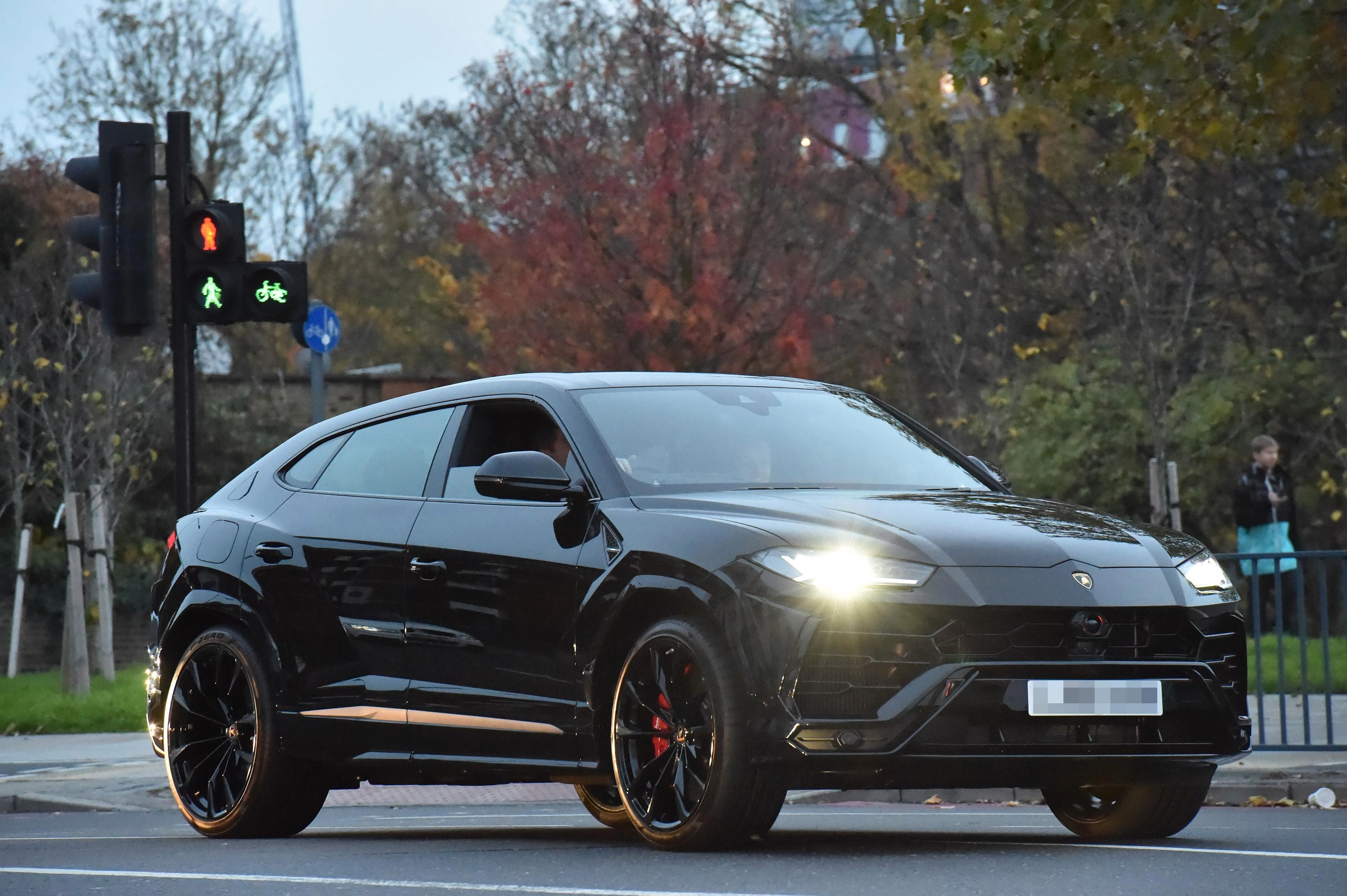 Simon Cowell driving his black Lamborghini Urus on the street