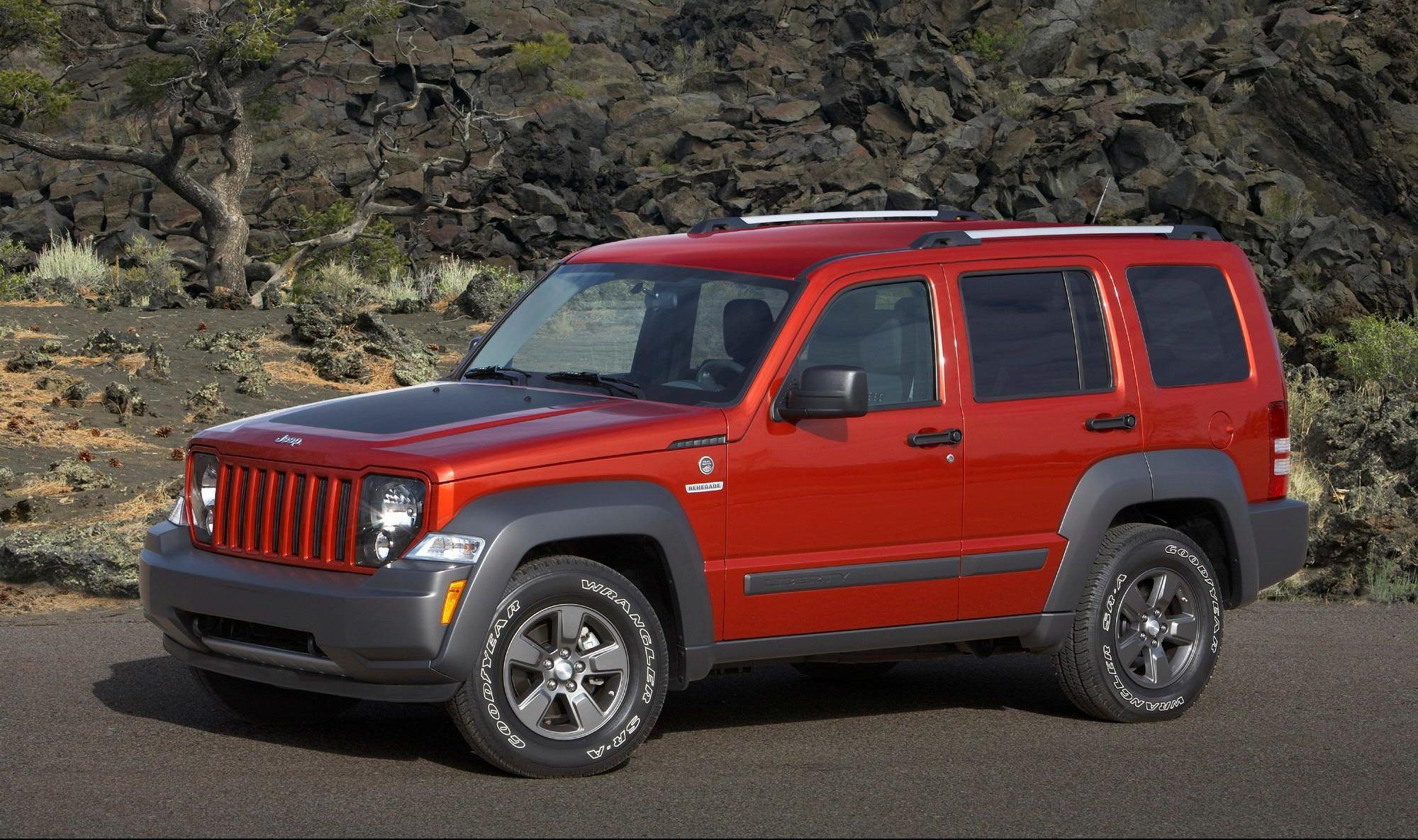 A red 2010 Jeep Liberty Renegade Edition is parked by a mountainside.