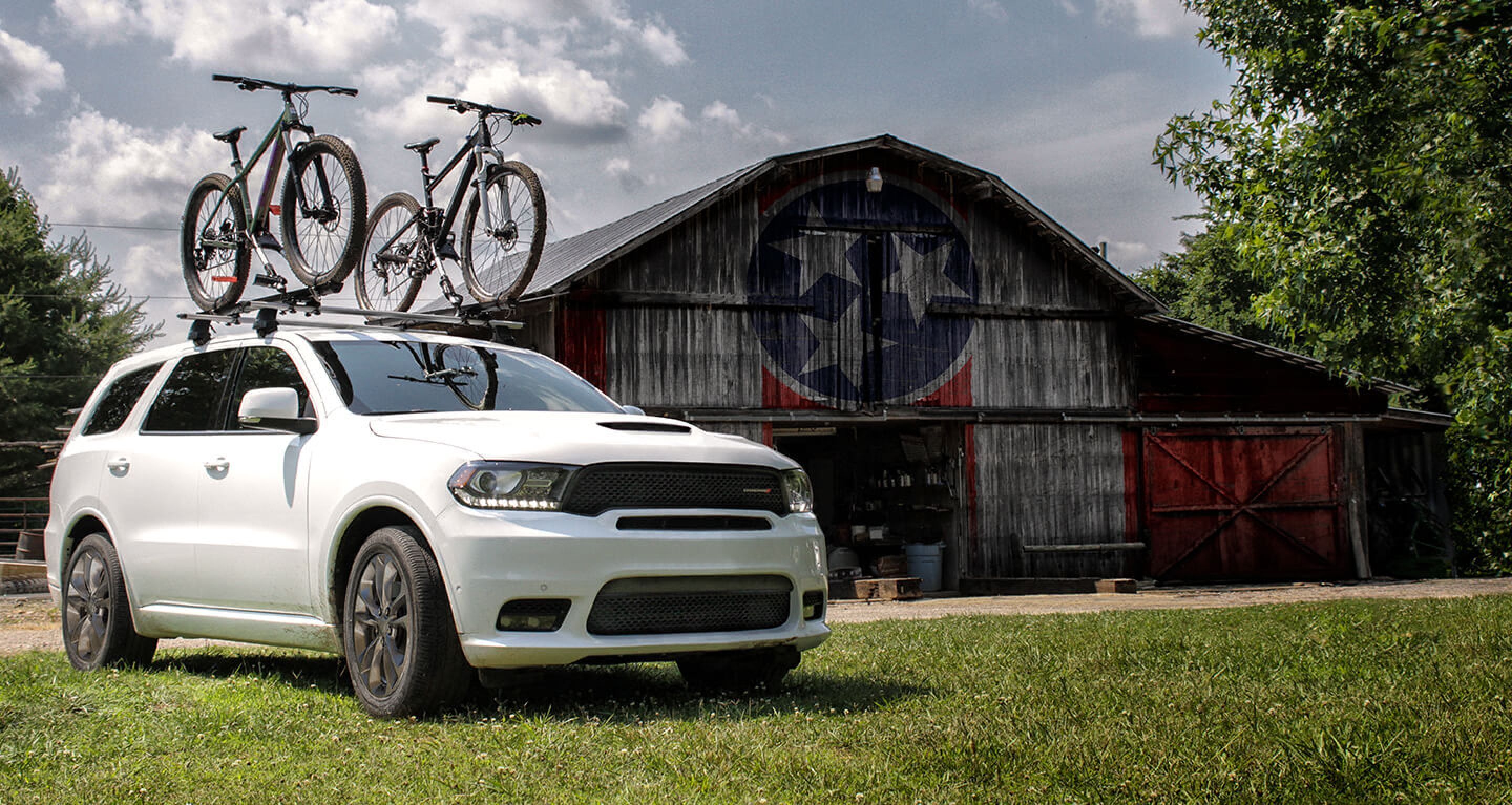 Dodge Durango with bikes on the roof in front of an old barn