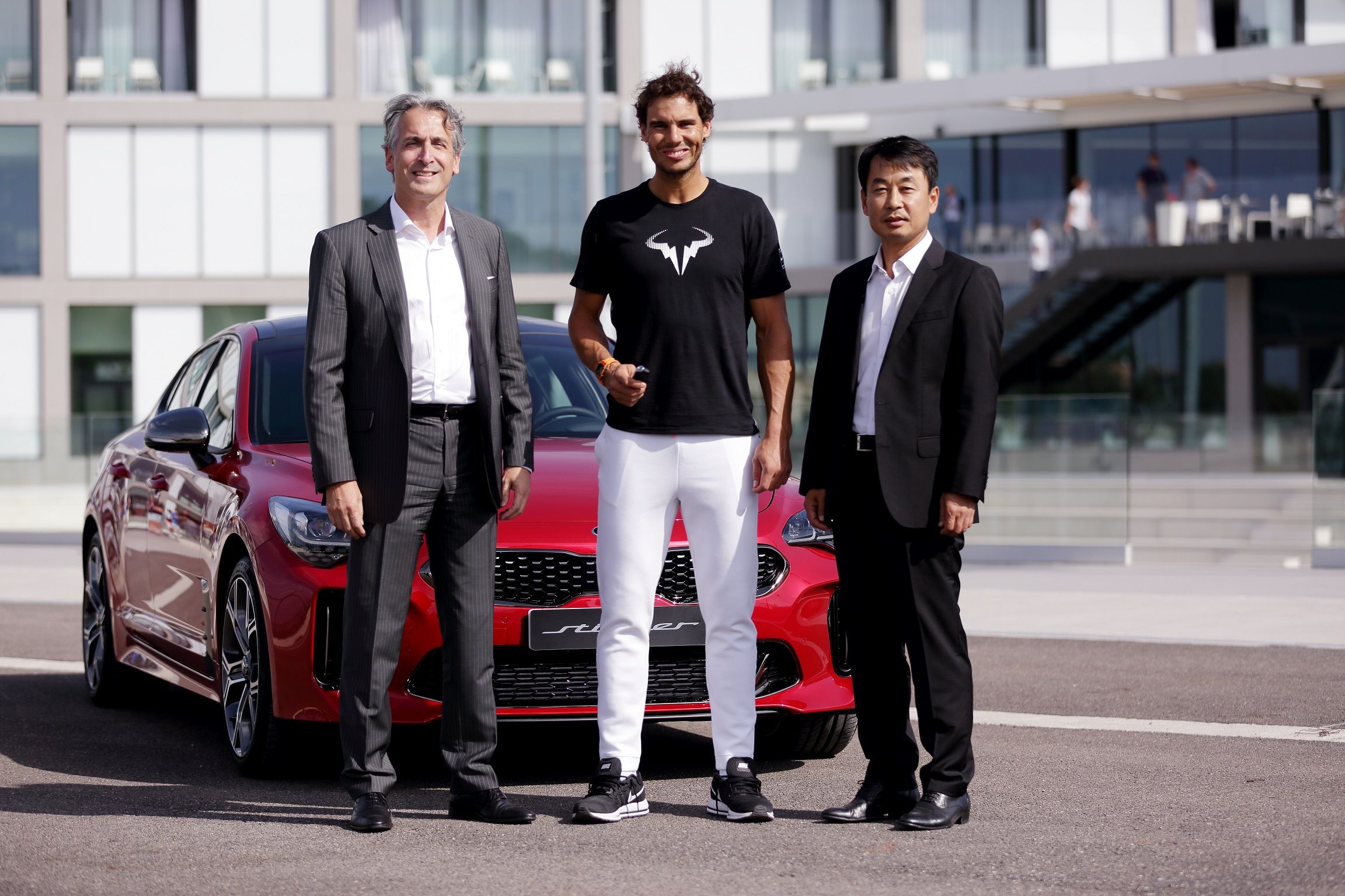 Rafael Nadal standing in front of a Kia Stinger with Kia executives