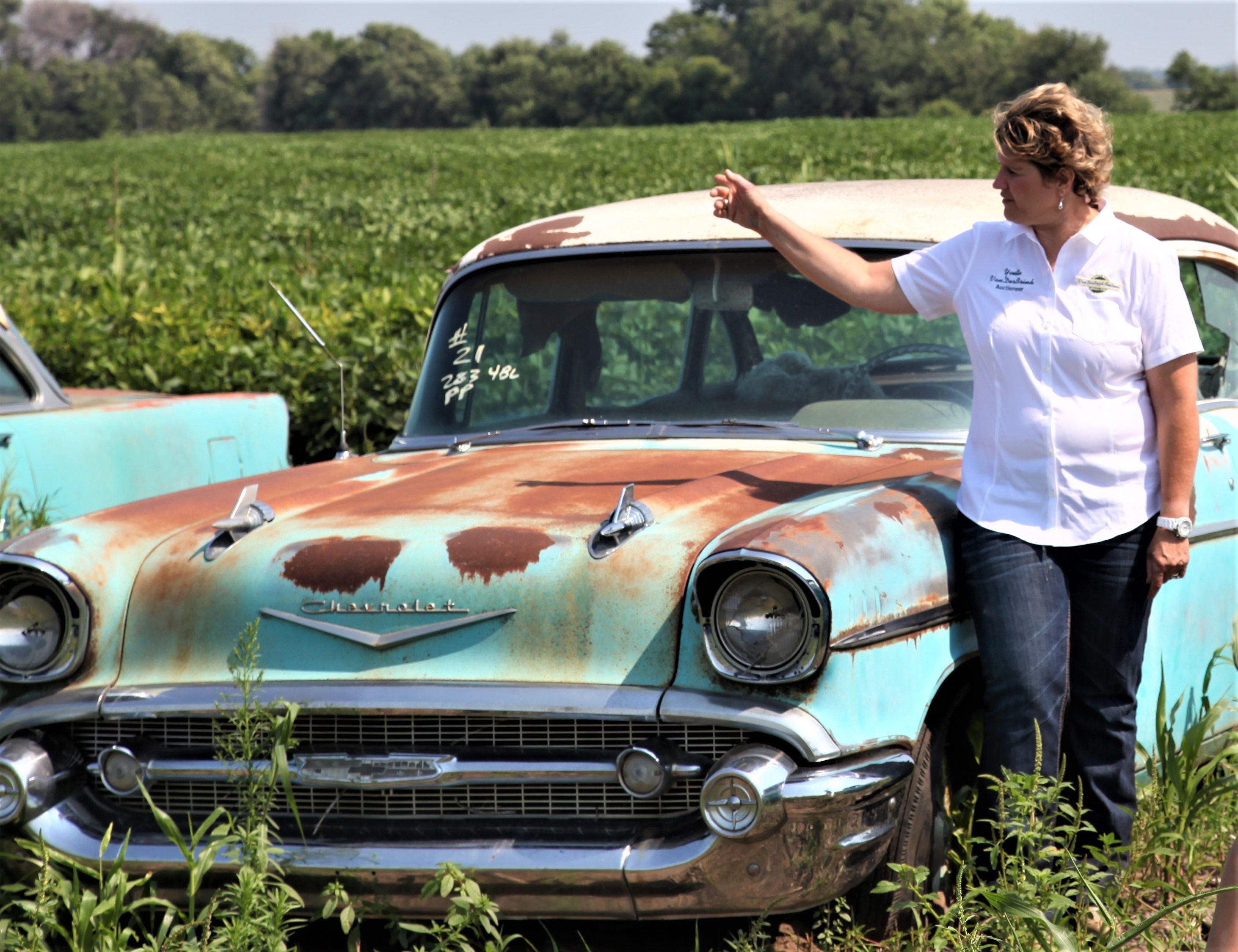 Woman standing next to classic car with rust