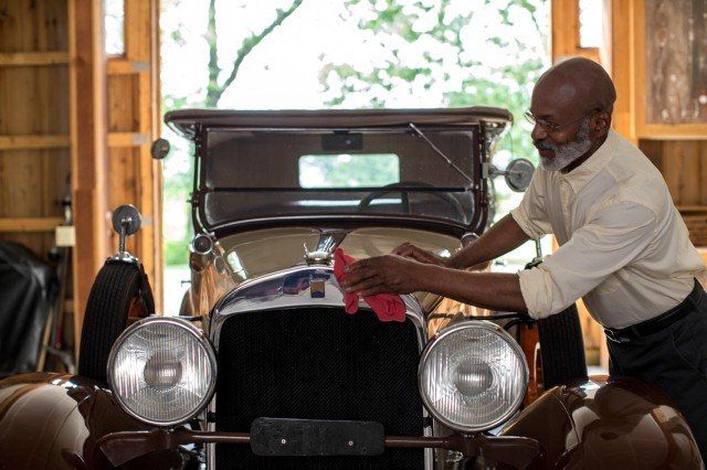 Man cleaning front of classic car