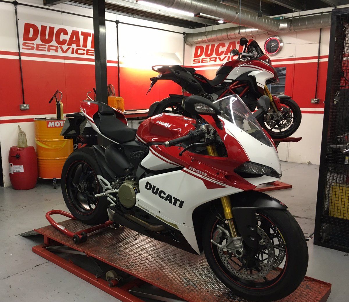 Two Ducati motorcycles on work benches in a repair shop