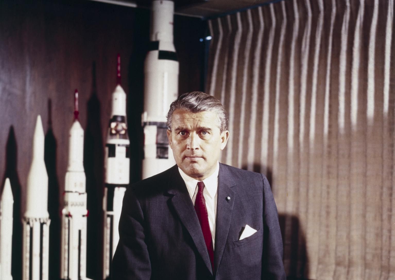 Wernher Von Braun posing in front of rocket models