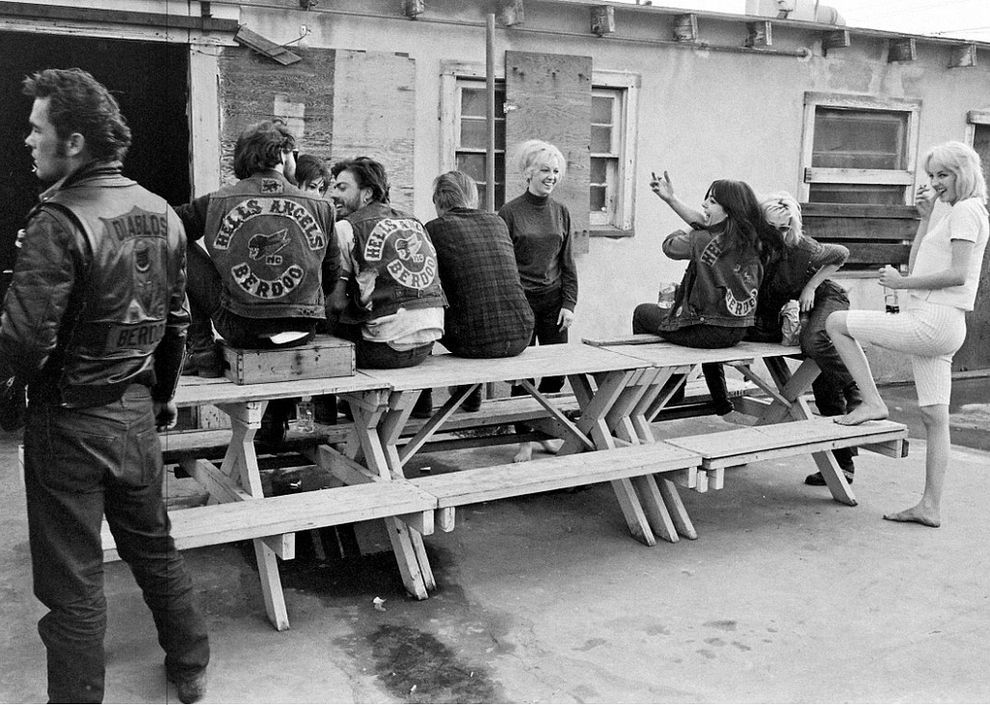 Riders gather and laugh around a picnic table as they enojy some down time together.