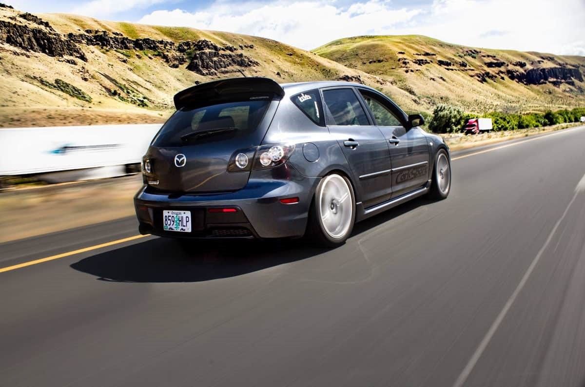 Grey Mazdaspeed 3 driving fast rear view