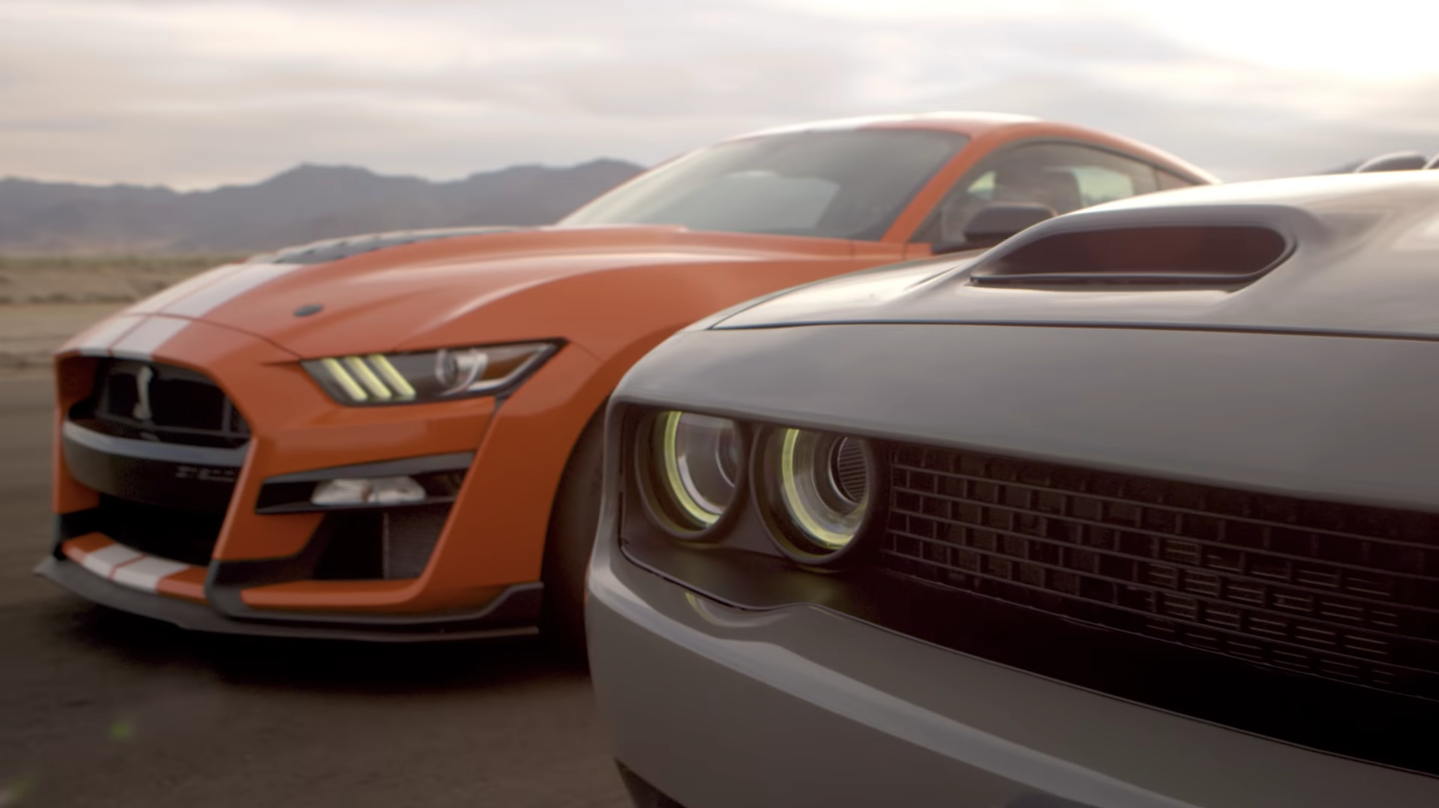 orange Ford Shelby GT500 behind a grey dodge challenger hellcat