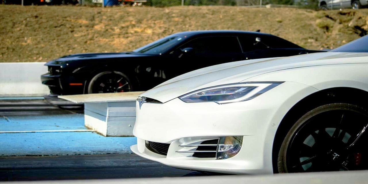 white tesla in front of a black hellcat on a drag strip