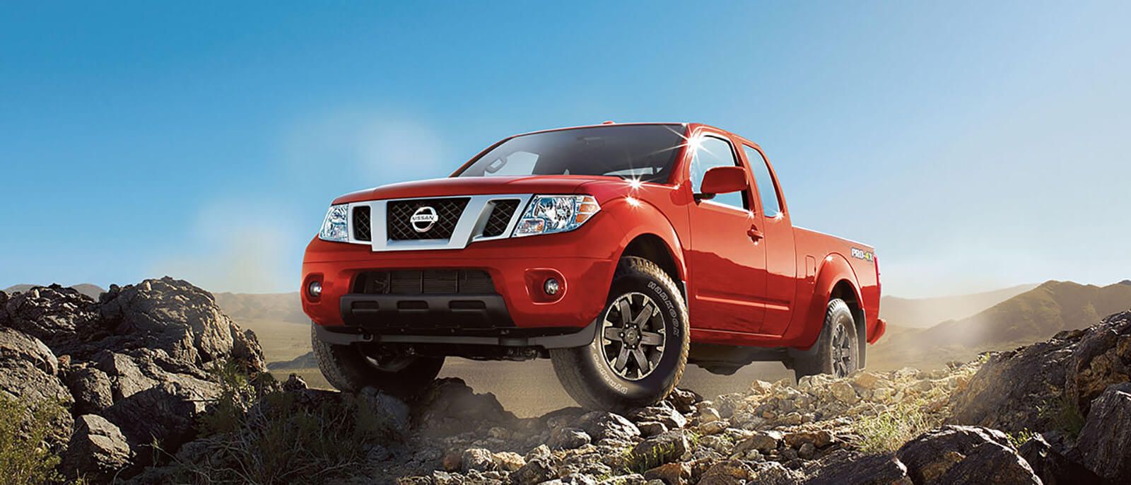 2017 Nissan Frontier driving on rocks with a blue sky background
