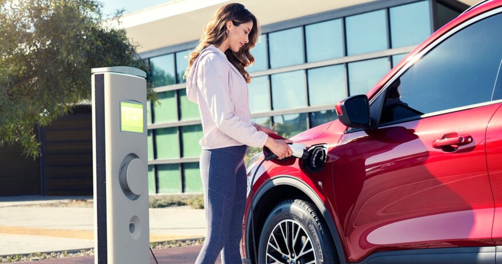 A woman plugs her Ford Escape in for charging