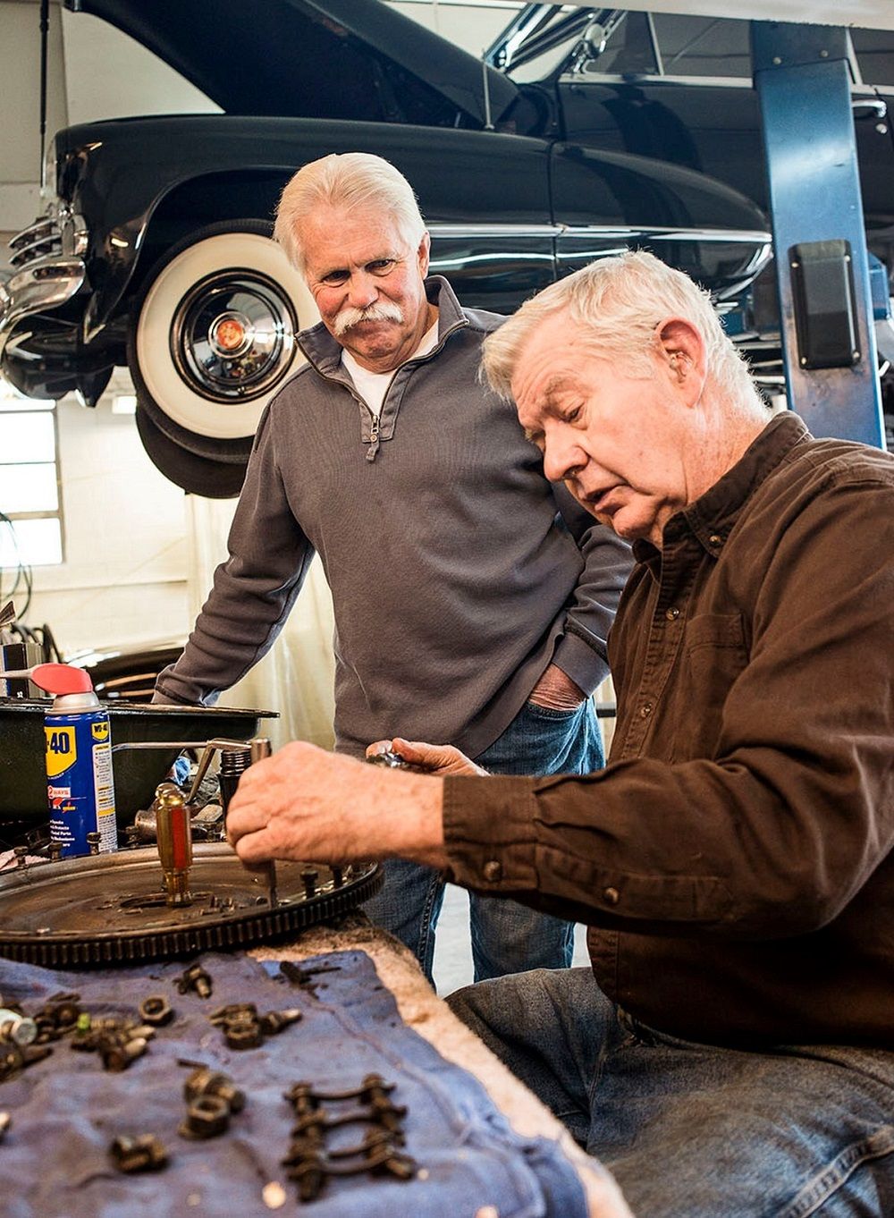 Two Old Friends Inspecting Car Parts Together