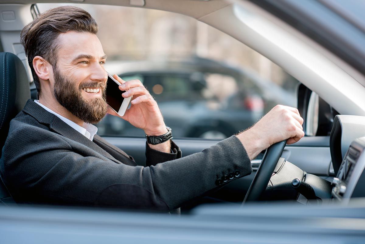 Handsome businessman talking with phone while driving a car in the city