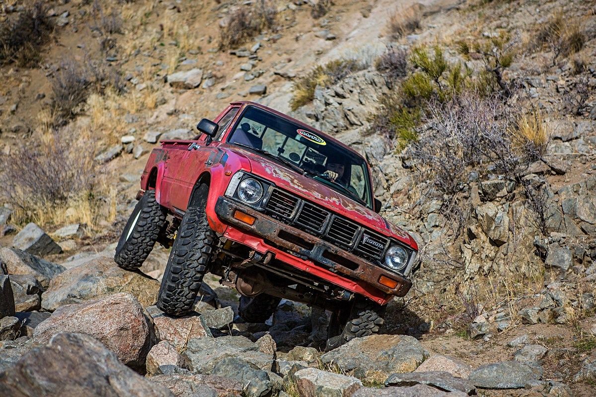 Red 1979 Toyota Hilux 4x4 driving over the rocks 