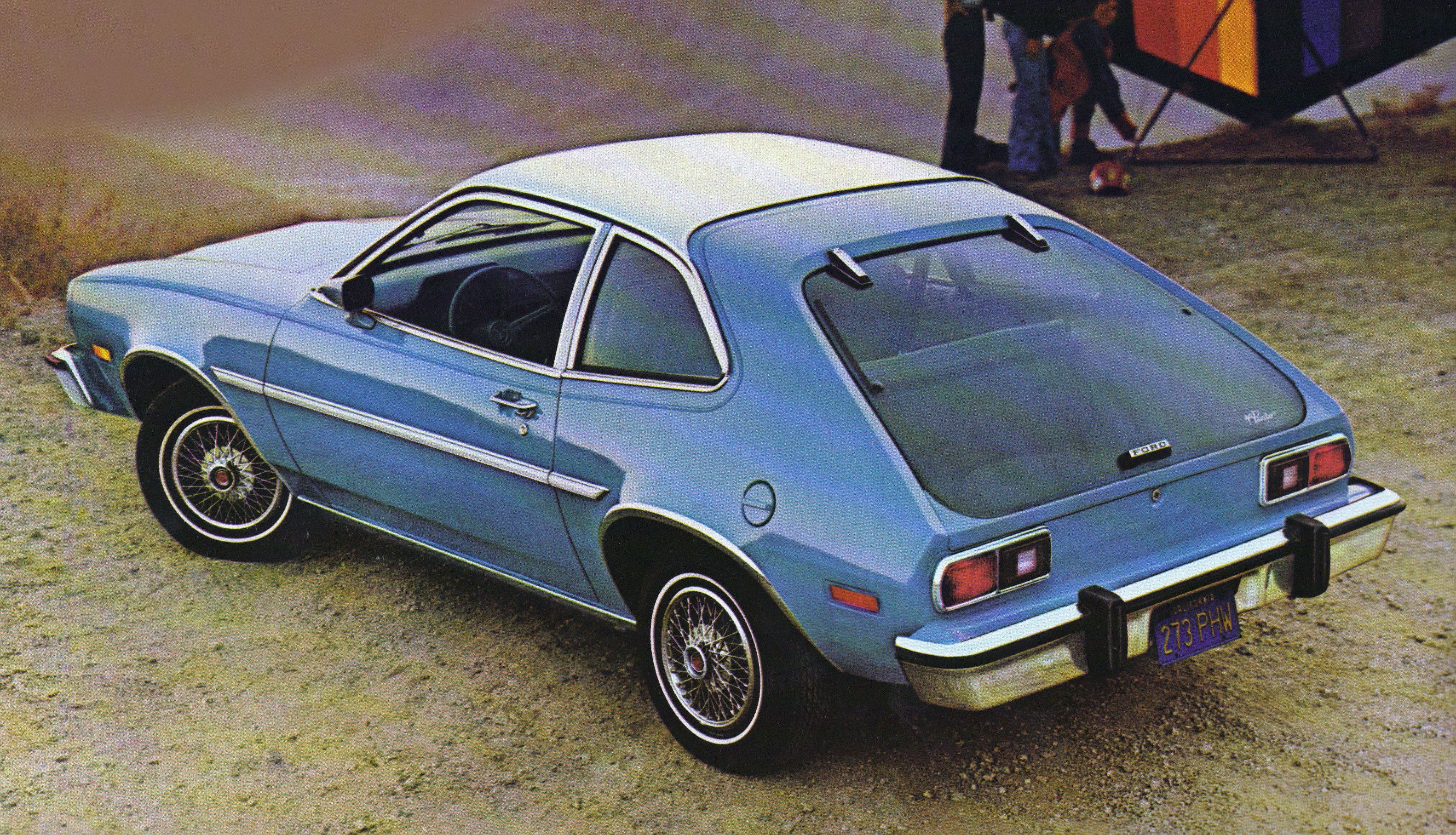 A blue Ford Pinto parked on dirt