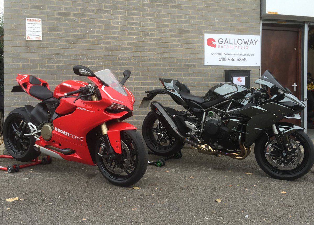 Ducati and a Kawasaki H2 parked outside of a motorcycle dealership