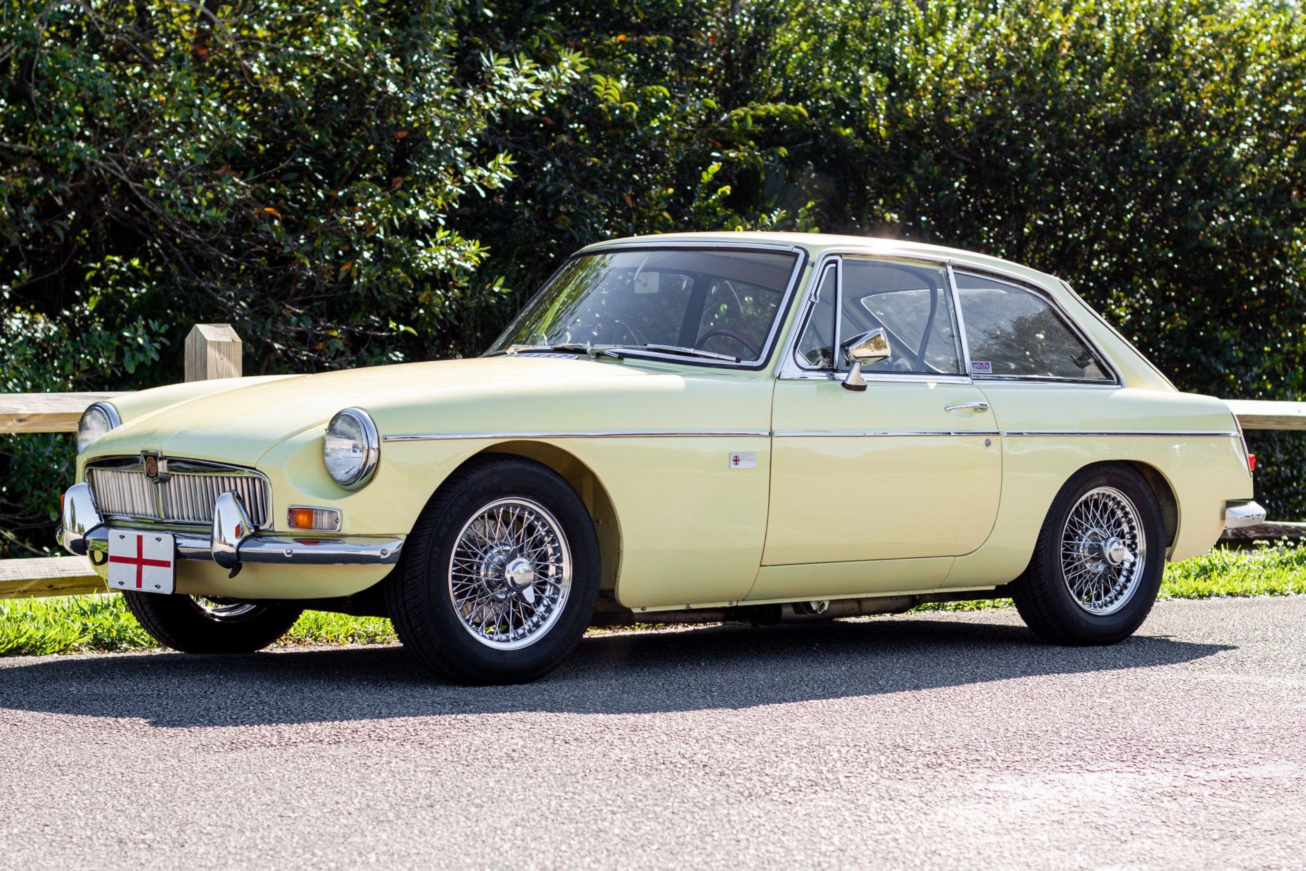 Pale Yellow MGB GT parked at the side of the road on a sunny day
