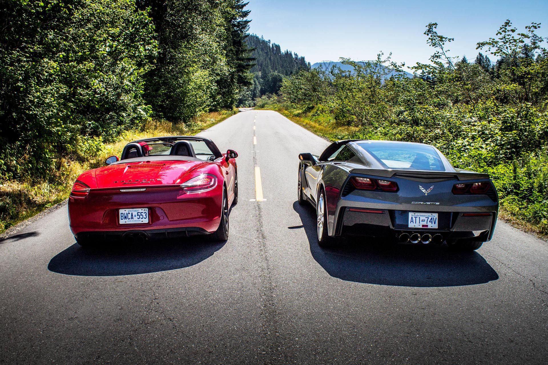 Corvette and Boxster drive down a deserted road in the mountains
