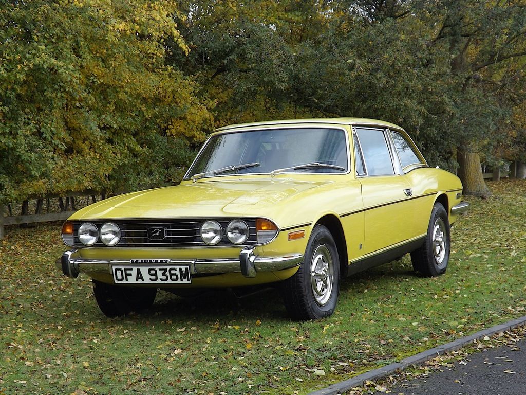 Inca Yellow Triumph Stag parked on the roadside lawns