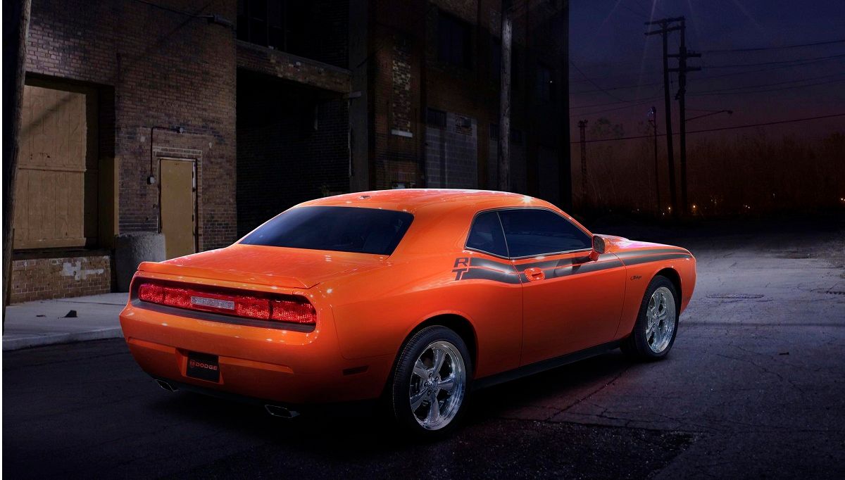 3/4 rear view of an illuminated Hemi Orange Pearl 2009 Dodge Challenger R/T Classic on an alley at dusk