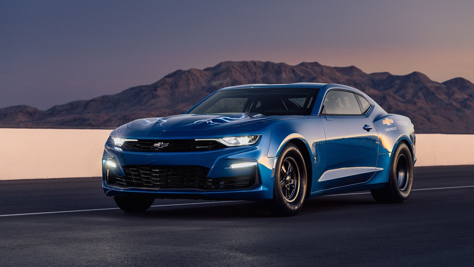 Riverside Blue Metallic 2019 Chevrolet eCOPO Camaro on the track at dusk with its headlights on