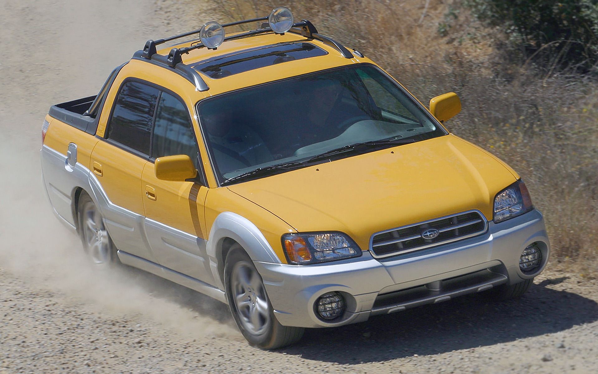 Subaru Baja yellow truck driving on dirt road