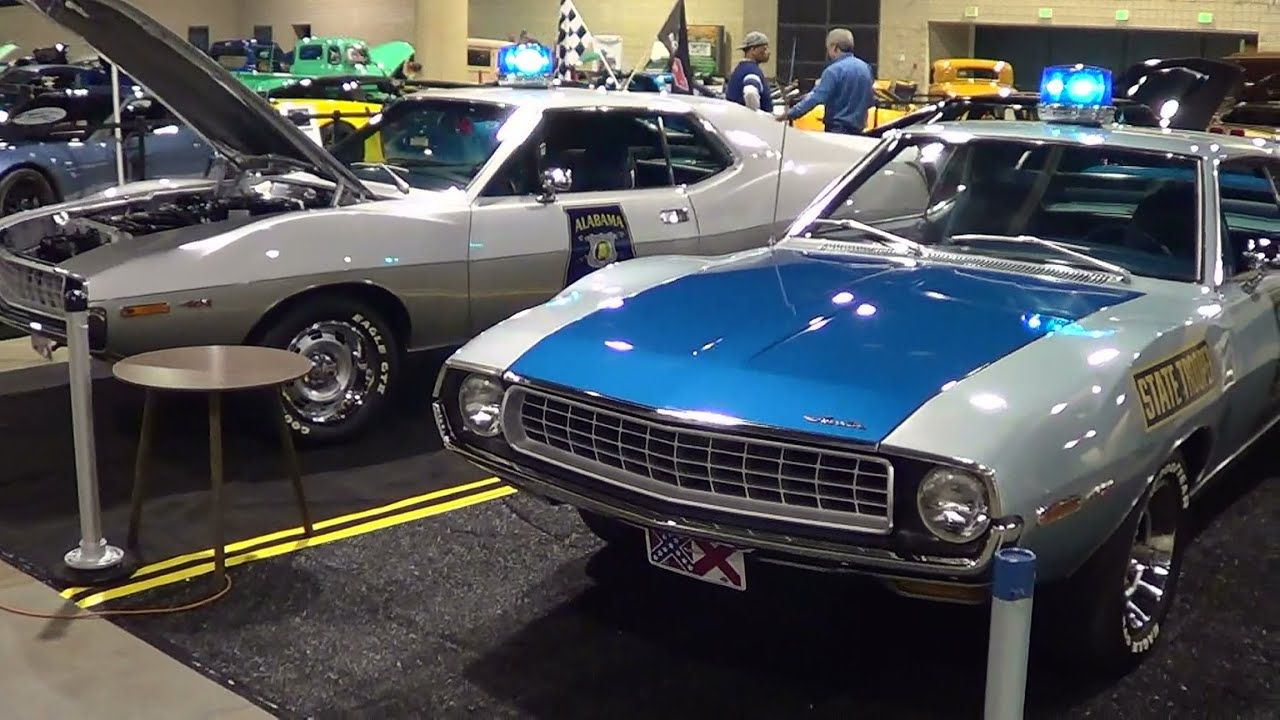Two silver police AMC Javelin AMXs with blue hoods at a classic car gallery