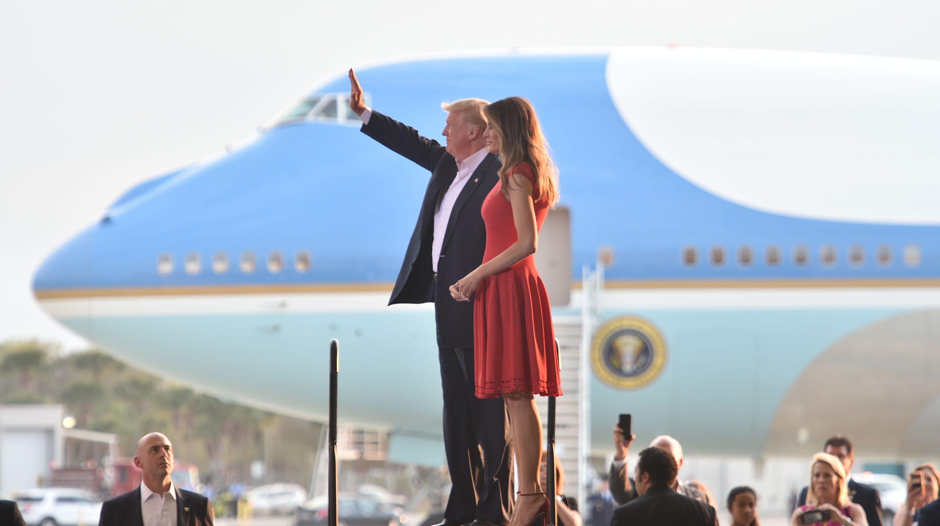 Trump and wife talking to people with plane in background