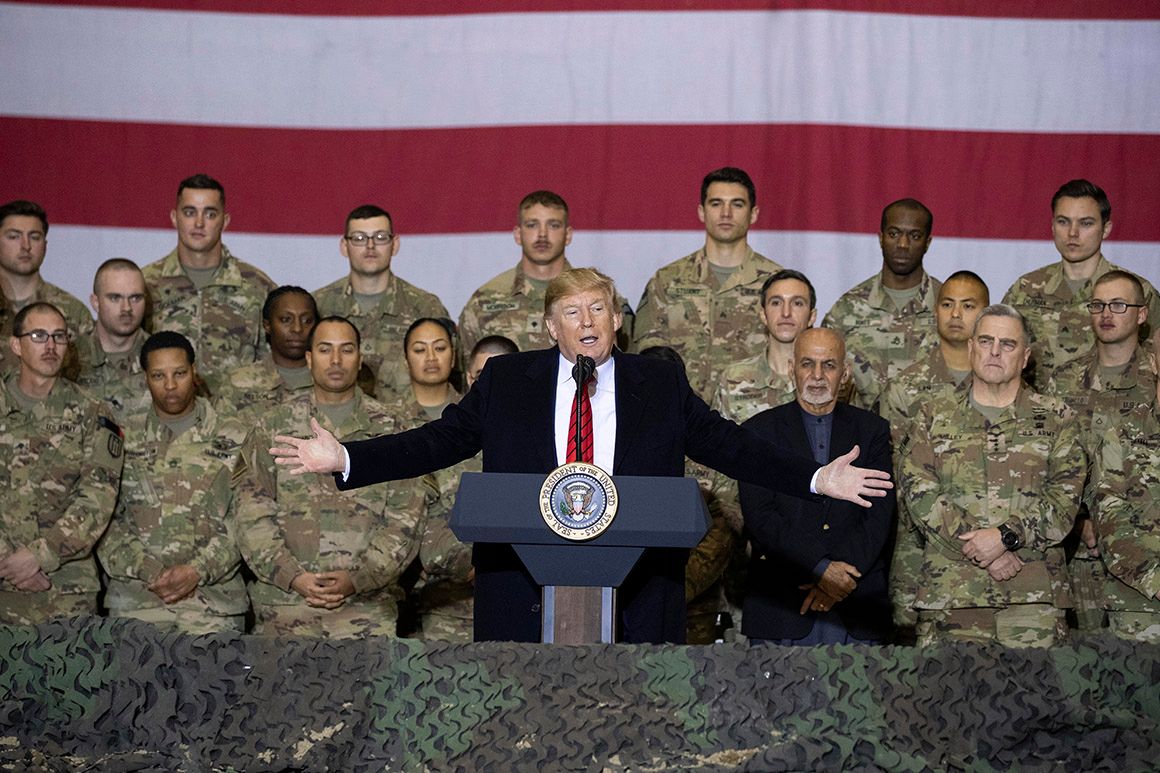 President Donald Trump with soldiers and a flag behind him