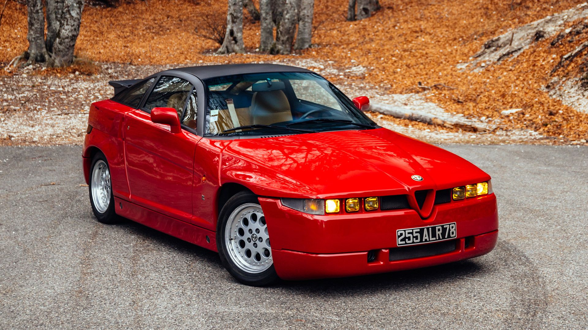 Red Alfa Romeo SZ on an autumn day with its daylights on