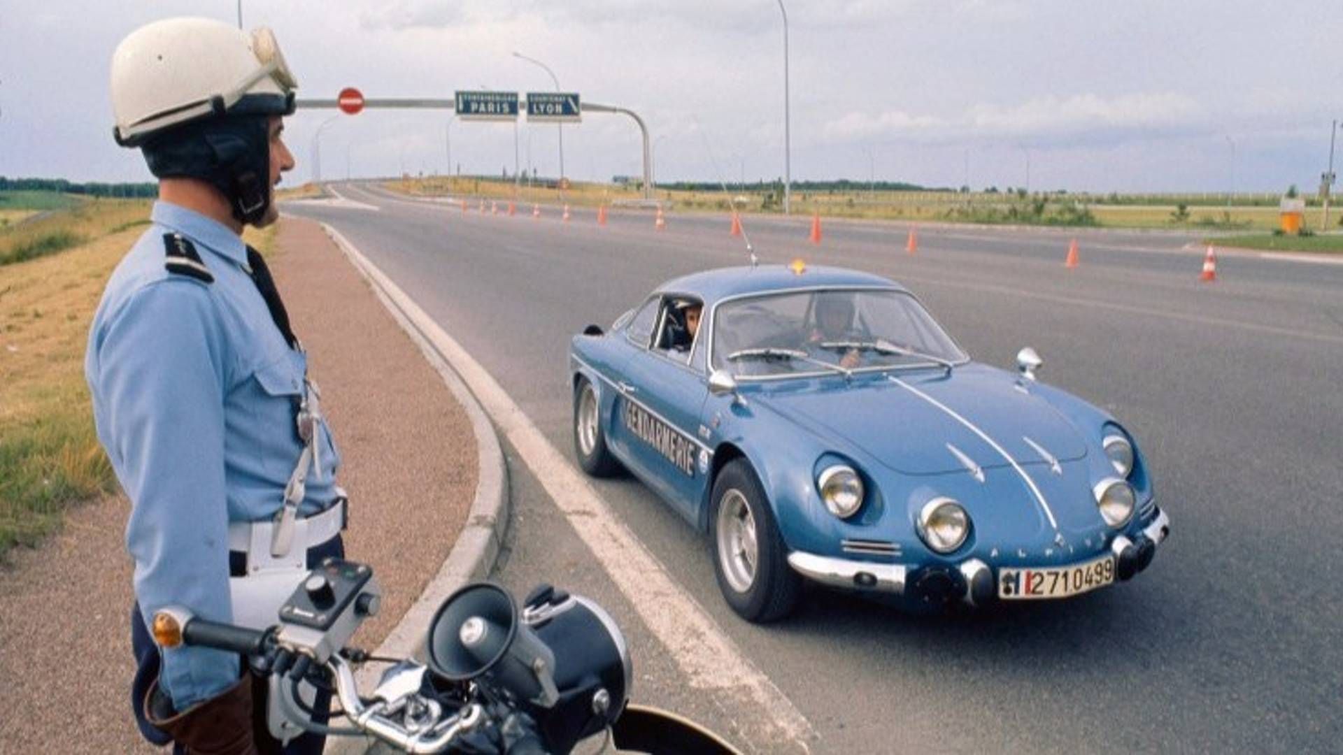 Blue Alpine A110 police car stopped next to a French motorcyclist police officer by a highway