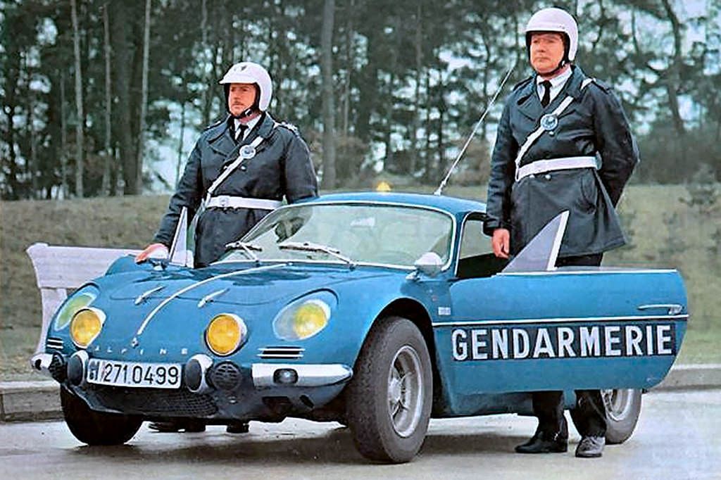 Two French police officers standing by a metallic blue Alpine A110 police car