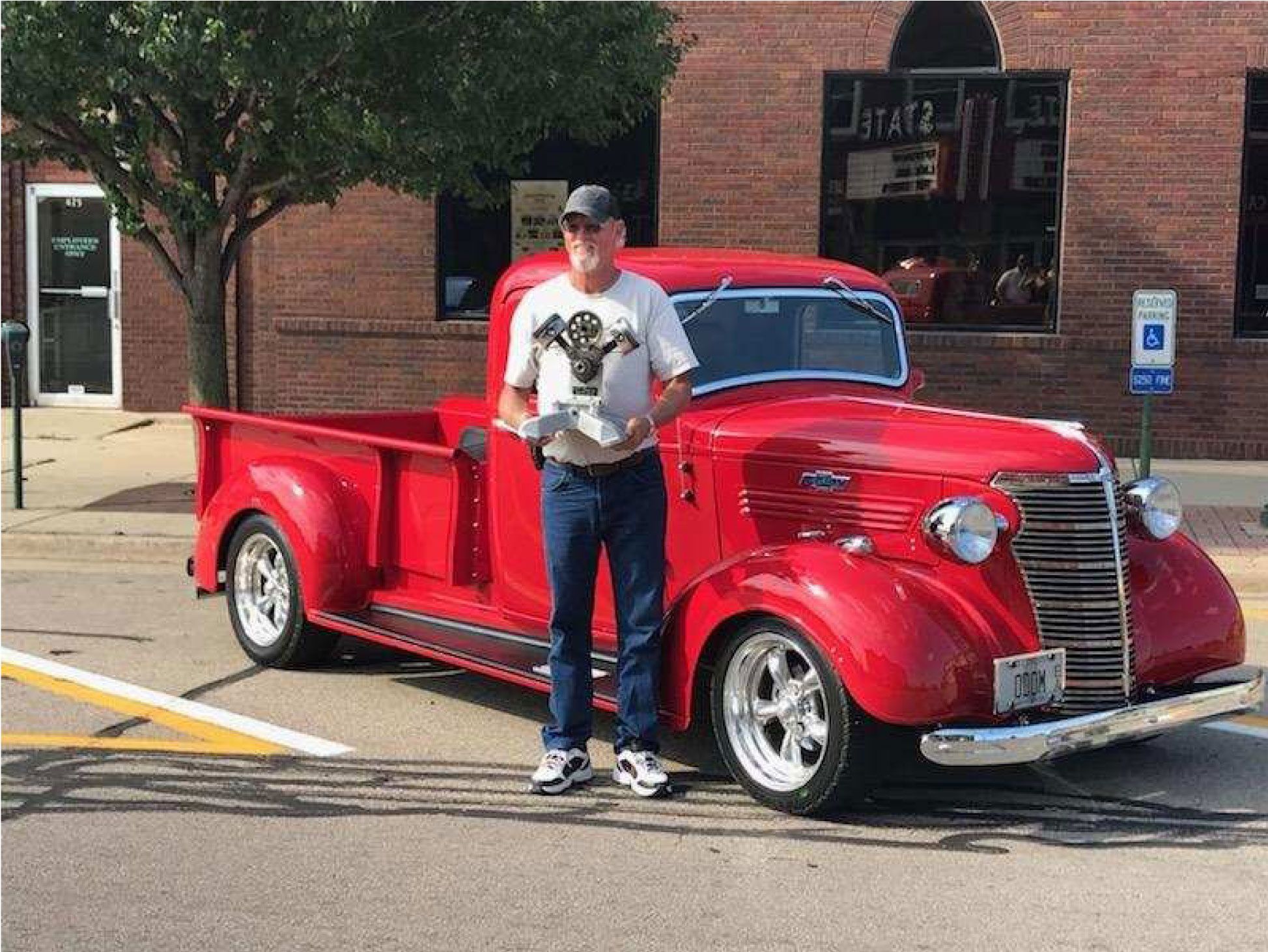 a guy standing beside his red classic truck
