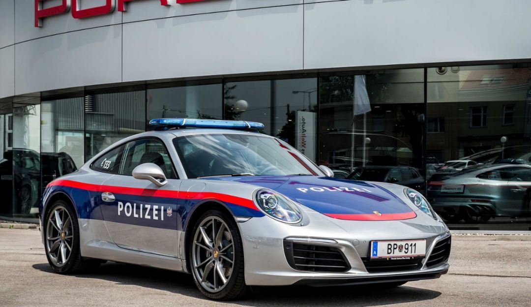 Porsche 911 police car in front of a Porsche showroom
