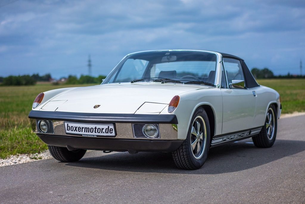 White Porsche 914 parked on the side of a road among fields