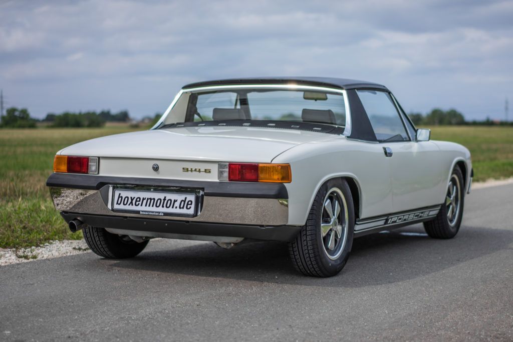White Porsche 914 parked on the side of a road among fields