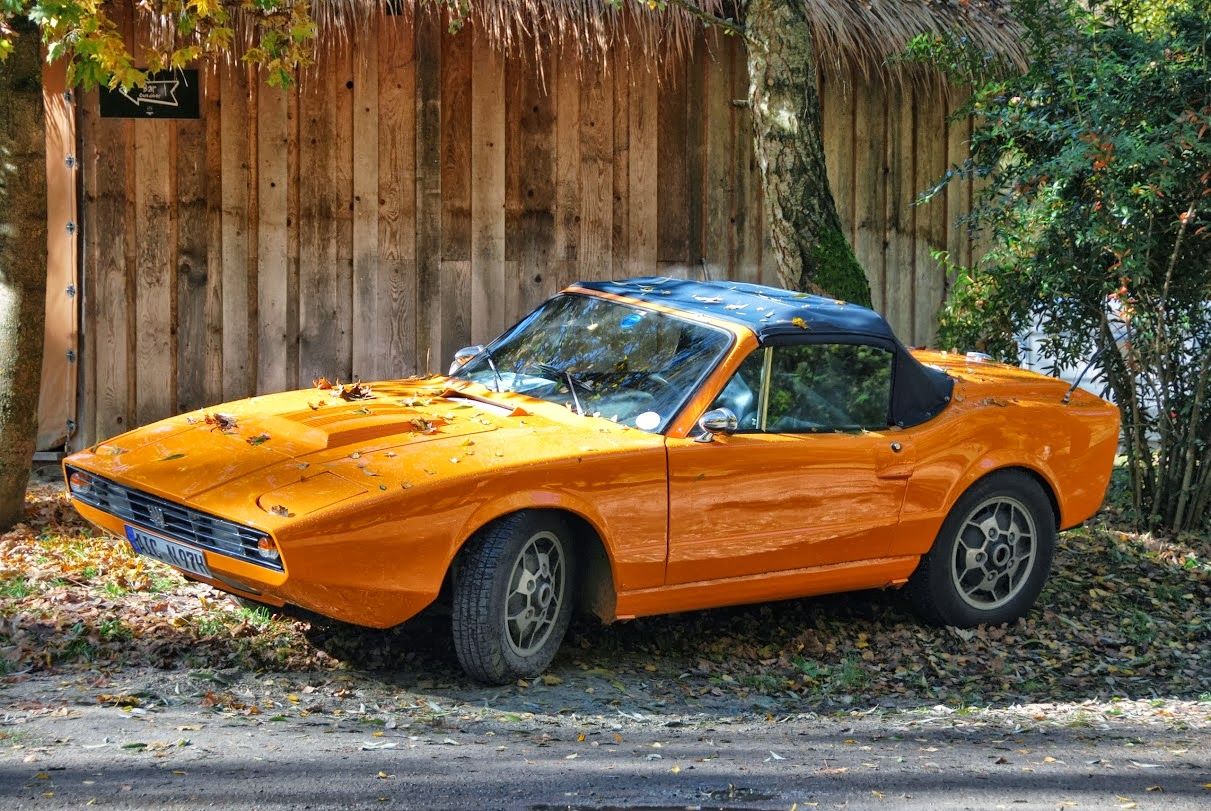 Orange Saab Sonett III parked on the autumn leaves on the side of a residential road