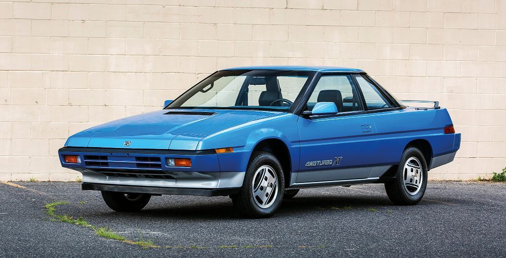Blue Subaru XT on the tarmac in front of a white wall