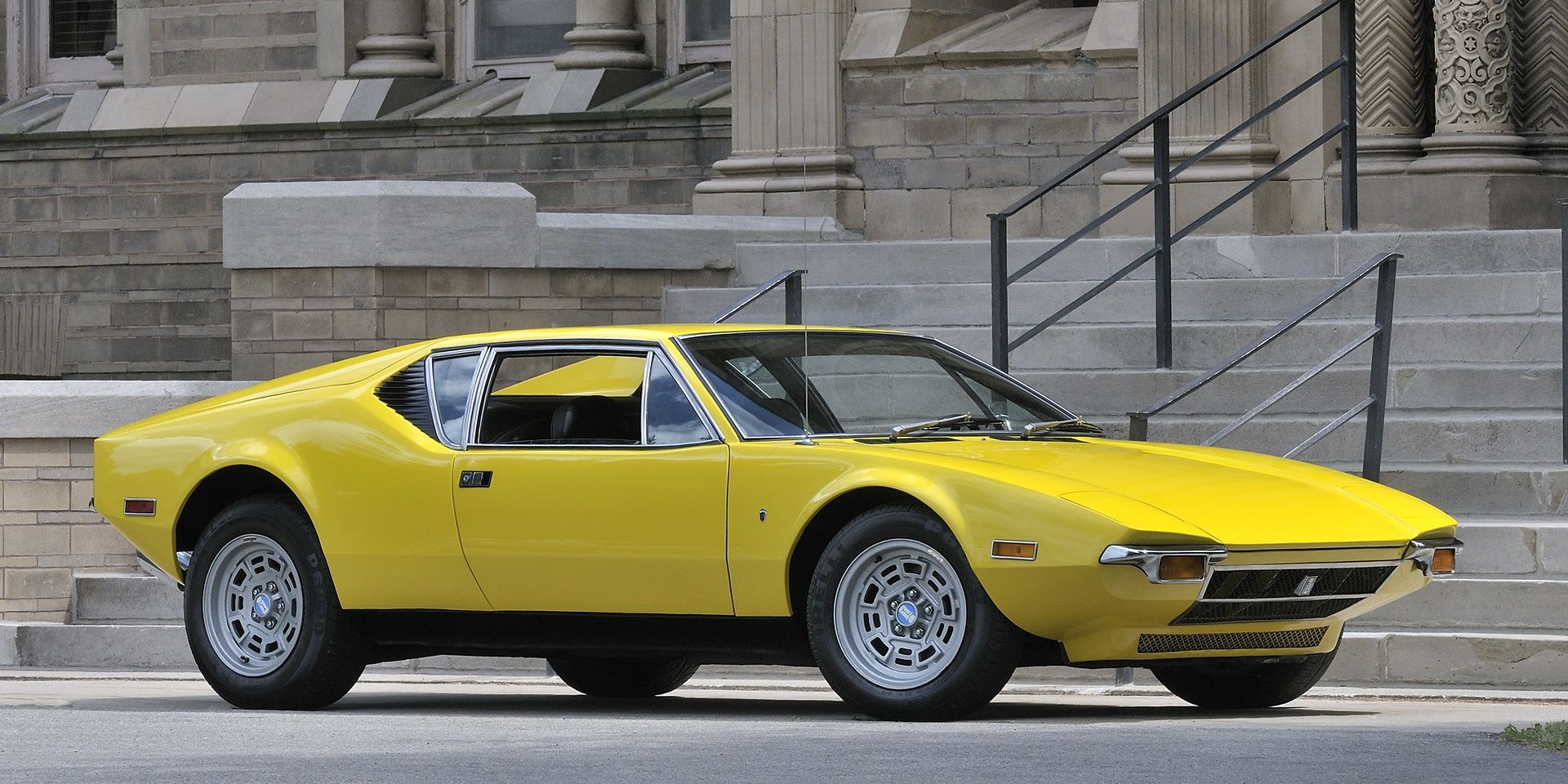A Classic Yellow 1971 De Tomasso Pantera Parked In Front Of The Stairs Of A Building
