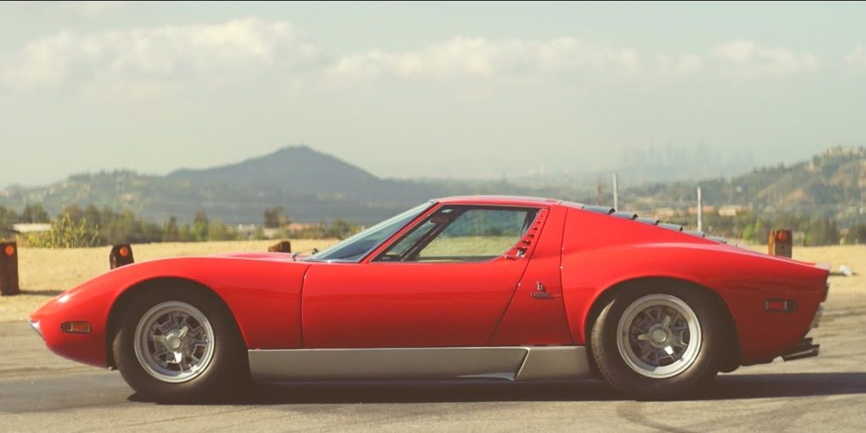 A Red And White 1971 Lamborghini Miura SV Parked In Front Of A Scenic View