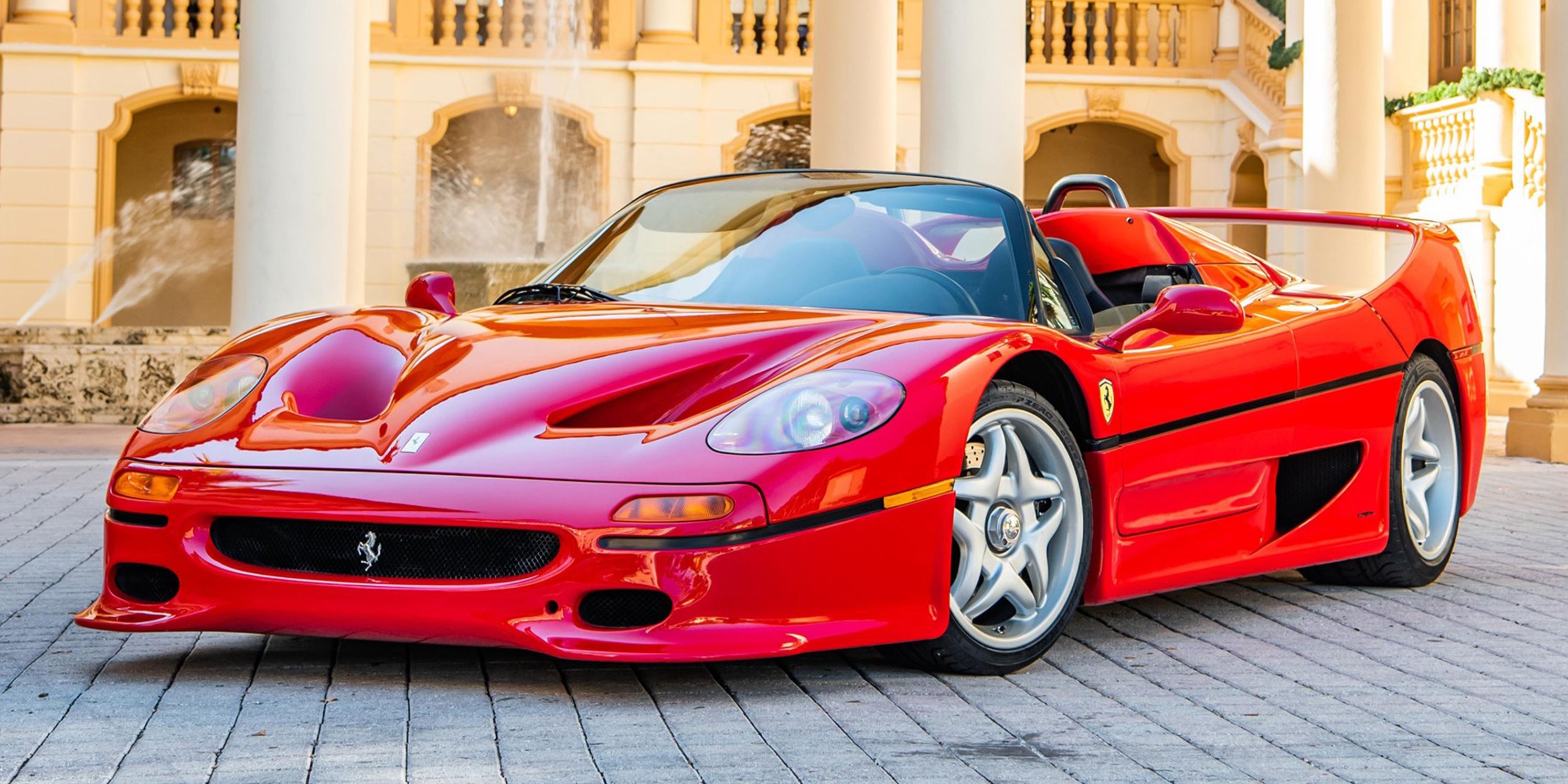A ravishing red 1995 Ferrari F50 parked on a cobbled ground