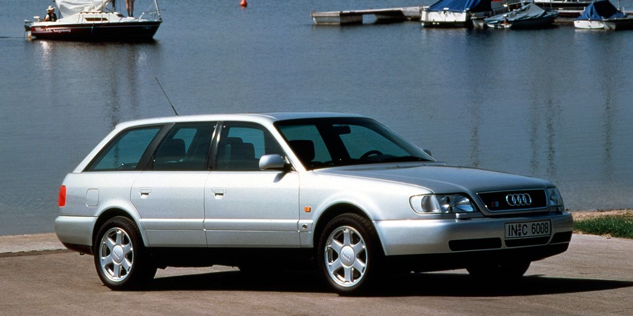 A silver 1996 Audi S6 Avant Plus C4 parked near the shore