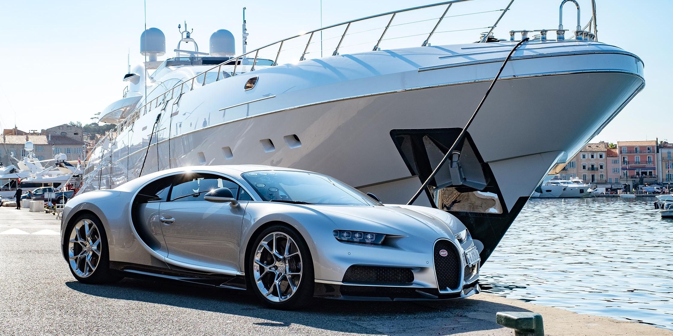 A silver Bugatti Chiron parked beside a luxury yacht