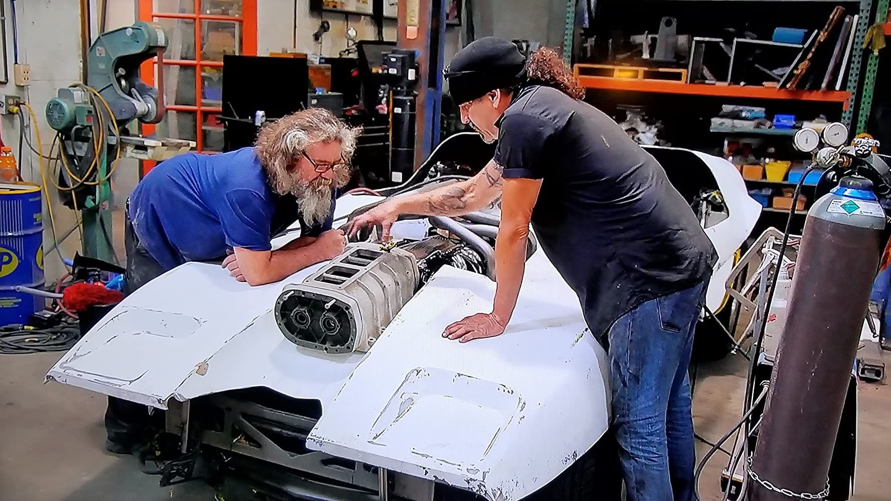 Mark and caveman working on a car