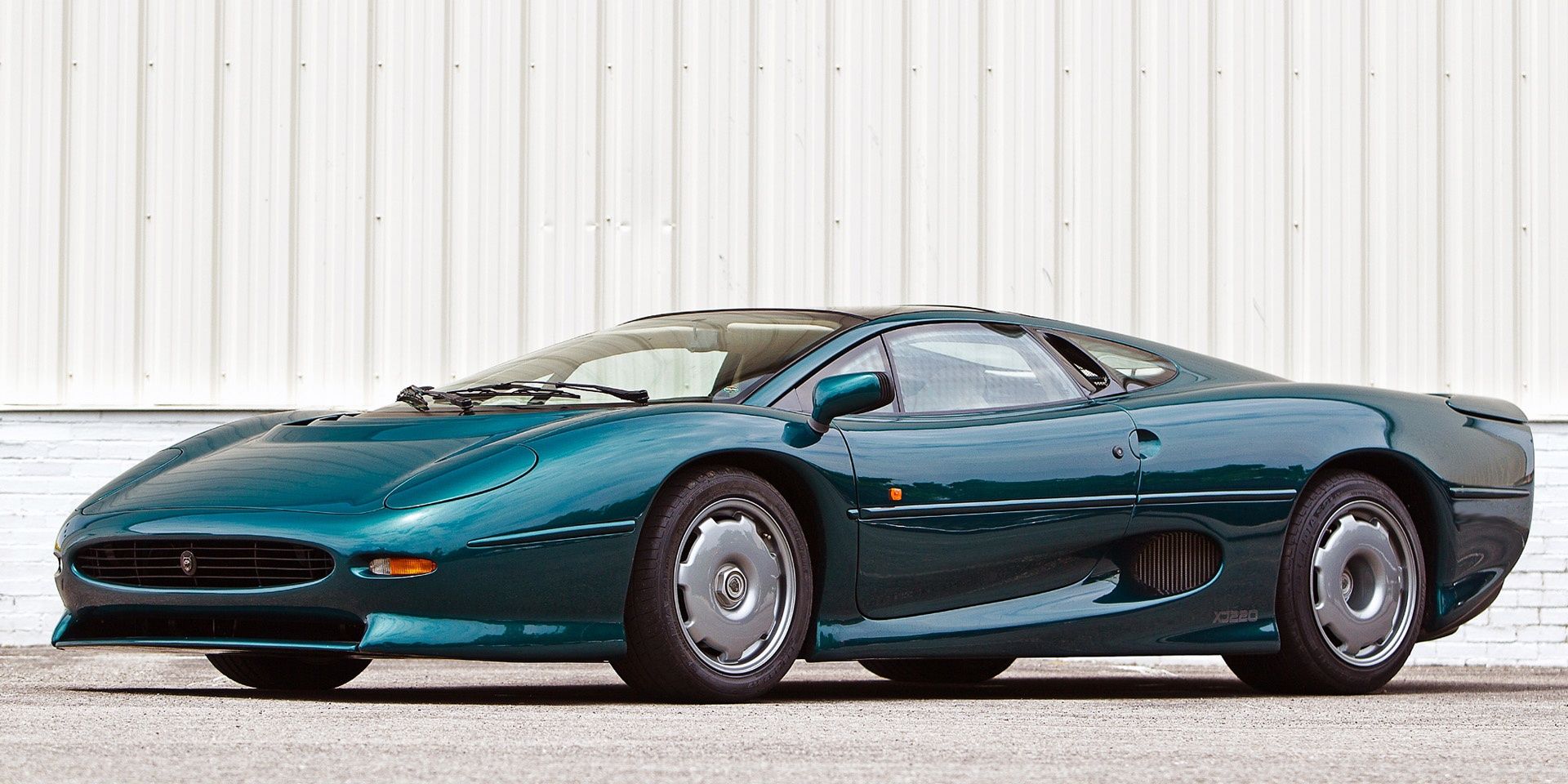An oceanic green 1992 Jaguar XJ220 parked and pictured against a white backdrop