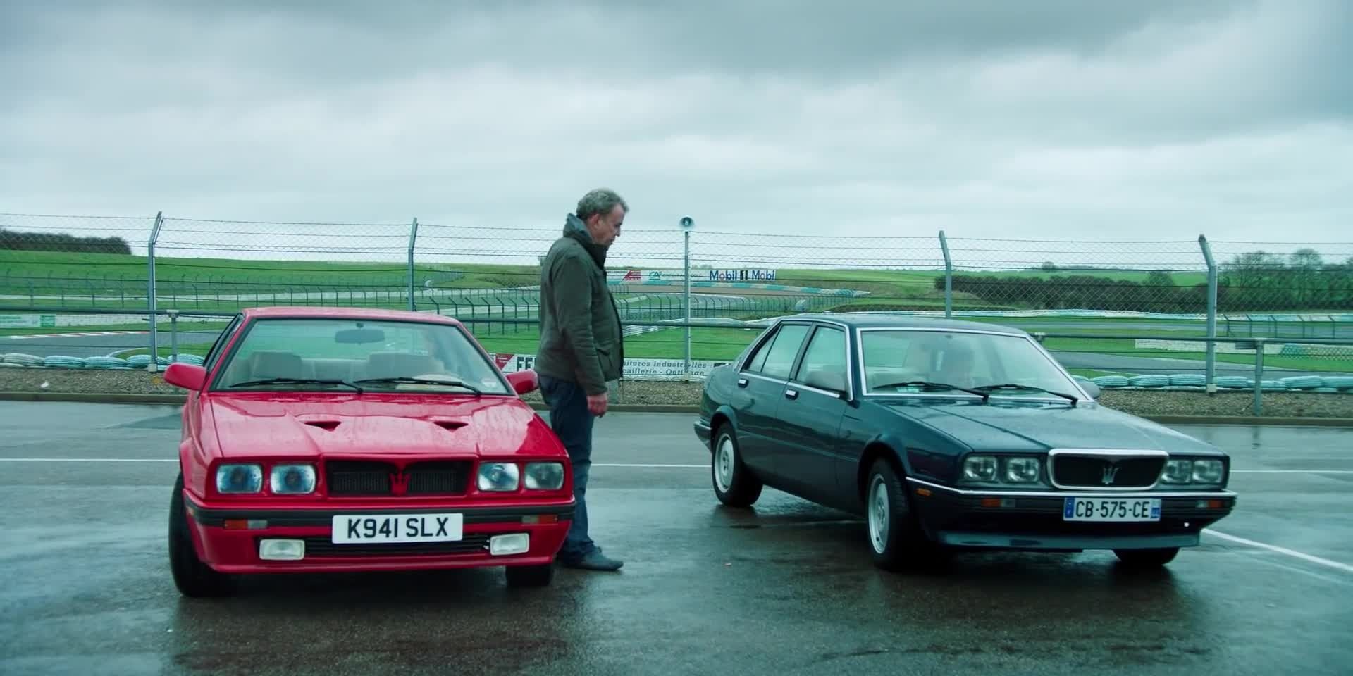 Clarkson standing beside a Maserati Bi-turbo S and looking at a 430 saloon driven by Hammond