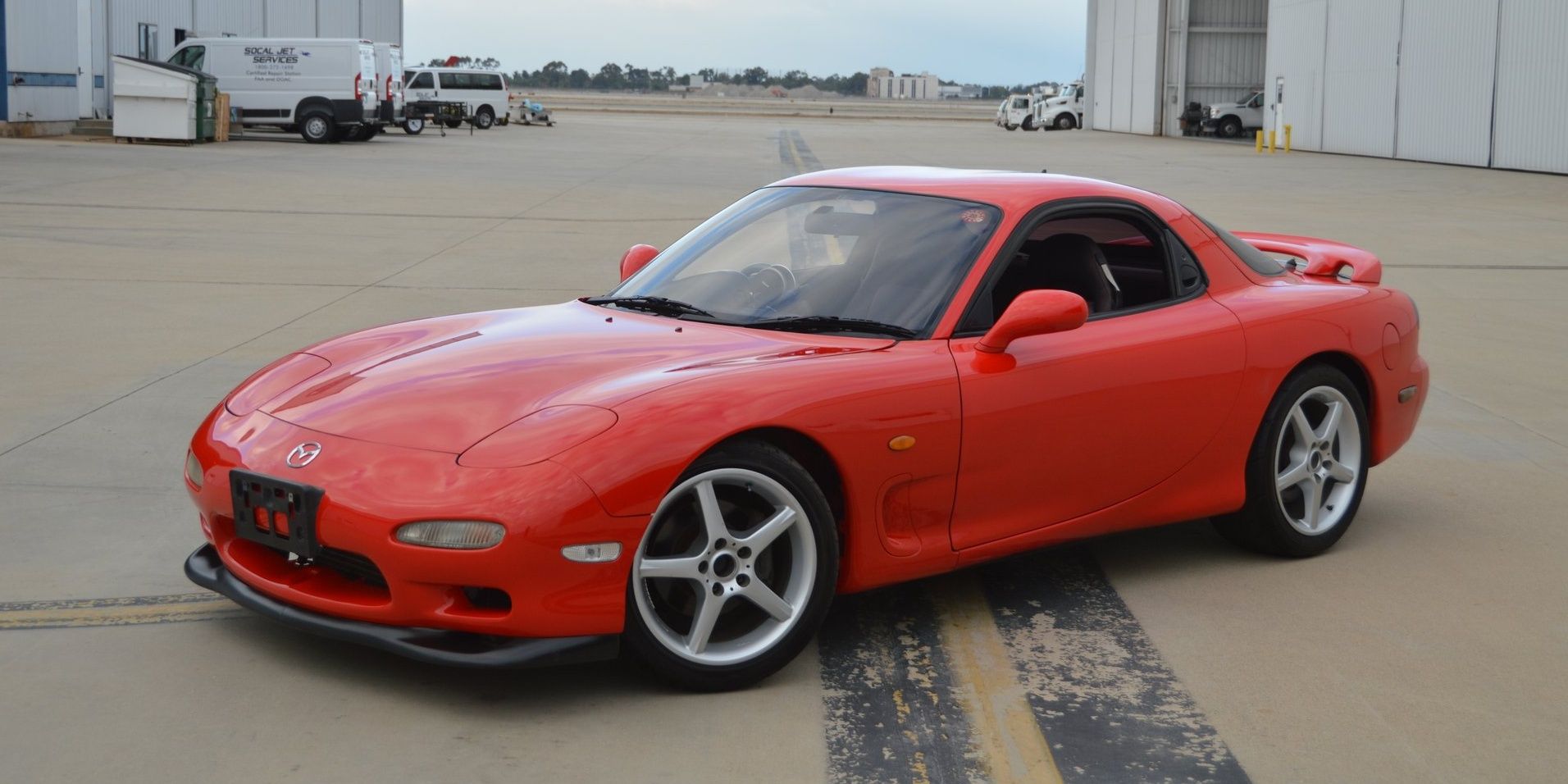 A red 1992 Mazda RX-7 parked inside an open compound