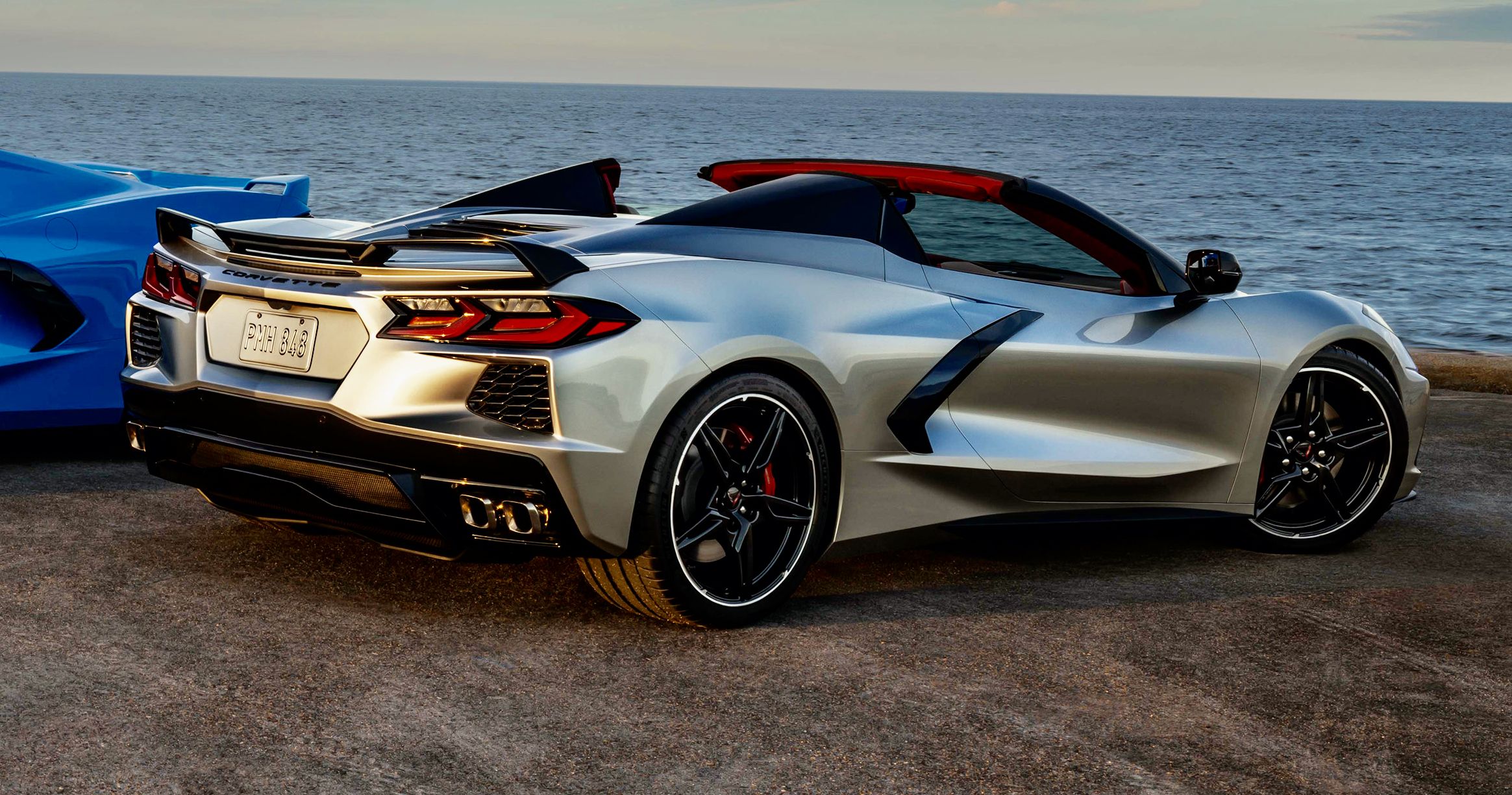 A 2021 Chevrolet Corvette C8 with stripes stands parked near the ocean.