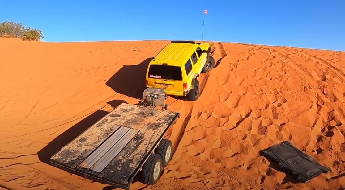 Recovery operator rolls flatbed trailer down a dune